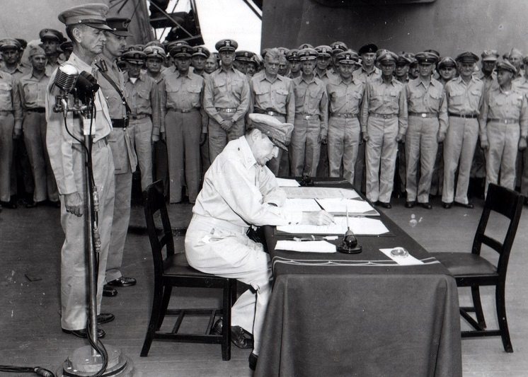 Macarthur signs documents during Japanese surrender.